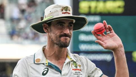 Australia fast bowler Mitchell Starc holds up the pink ball after taking a five-wicket haul in a day-night Test against India